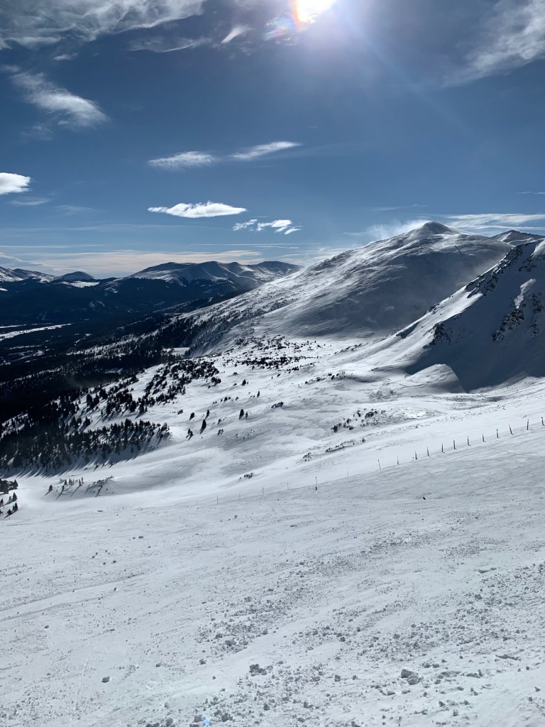 Snowy ski trail with trees in the background.