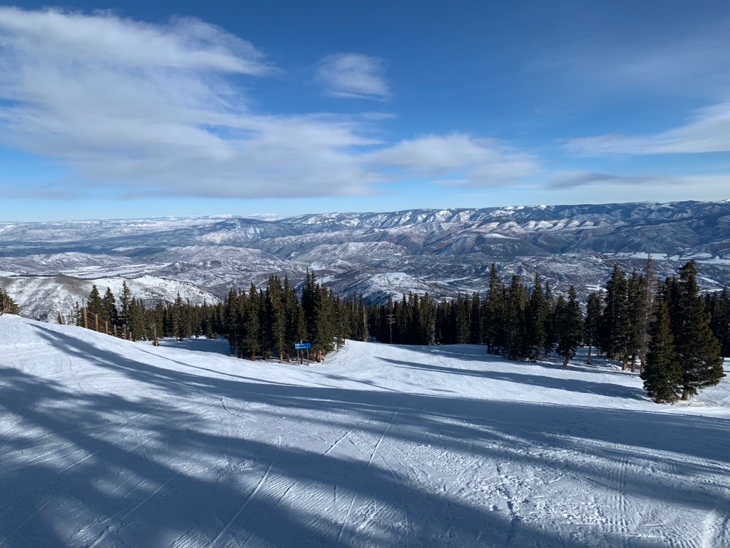 Ski trail with snow-covered mountains in the distance.