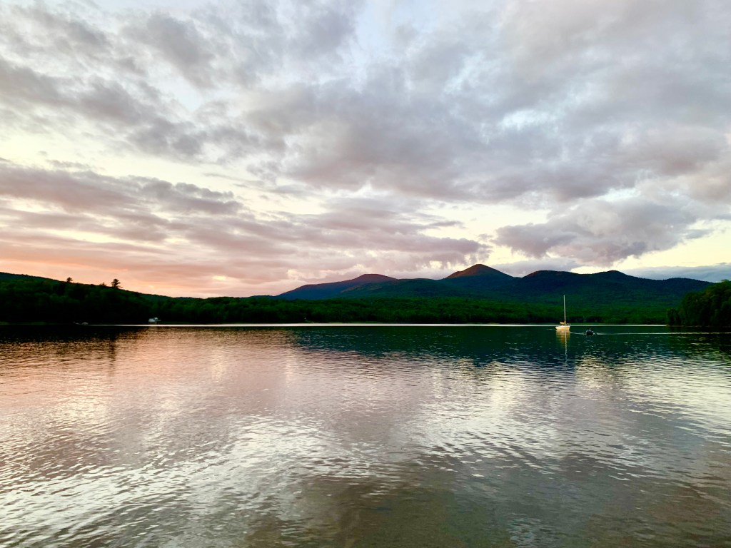 Calm water at sunset with mountains the background