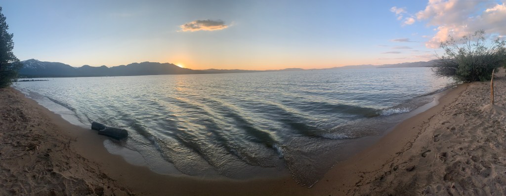 beach with sun setting behind mountain in the background