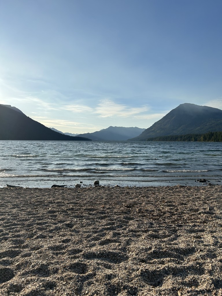 lake with mountains and sandy beach on a clear and sunny day